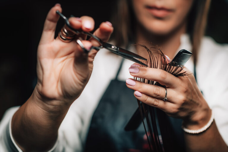 Close-up of a hairdresser cutting woman’s hair.