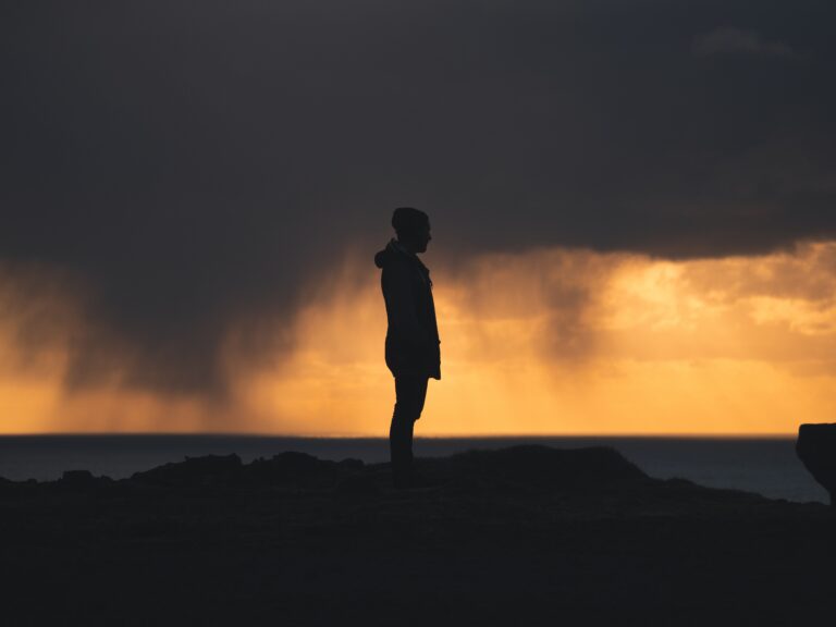 A person standing strong in a storm, illuminated by light, symbolizing perseverance through hardship