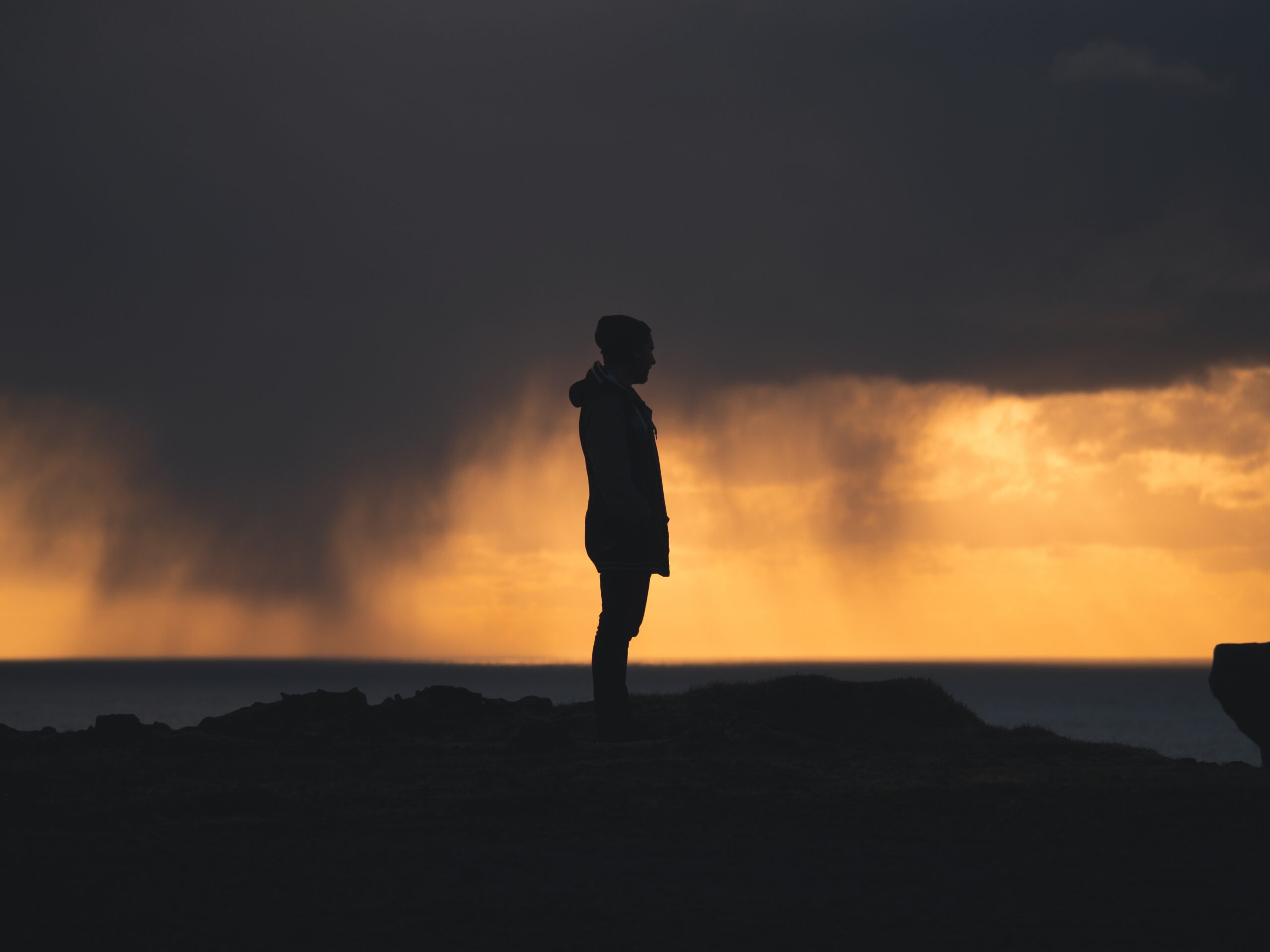 A person standing strong in a storm, illuminated by light, symbolizing perseverance through hardship