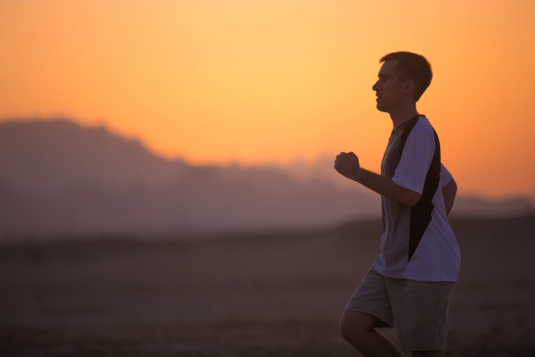 A runner nearing the finish line at sunrise, symbolizing perseverance and faith through hardship