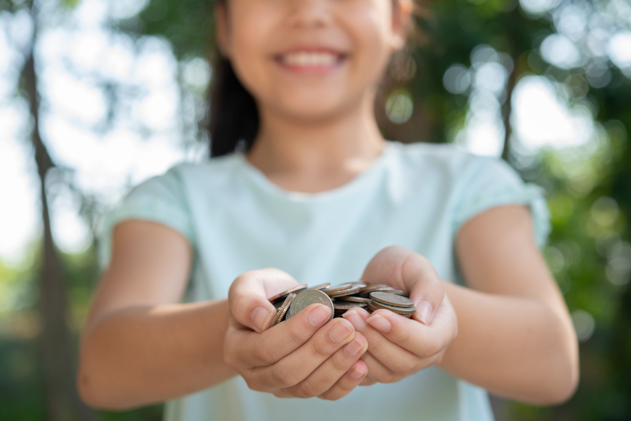 Hands holding coins in warm light, symbolizing generosity and faithful stewardship