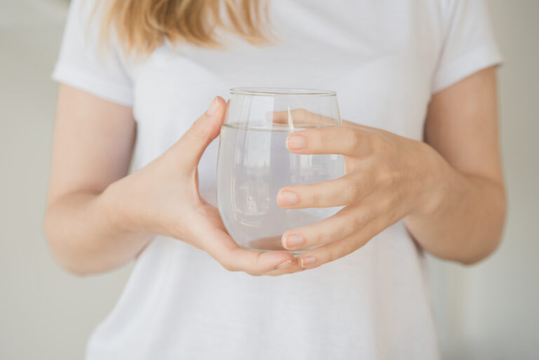 A hand offering a glass of water, symbolizing small, humble acts of service